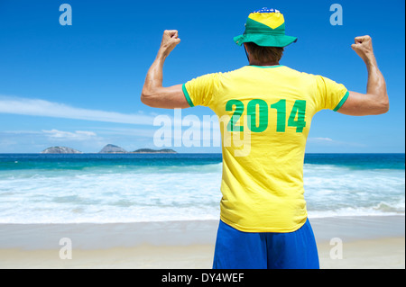 Uomo brasiliano nel 2014 shirt in colori brasiliano celebrando in tropicale sulla spiaggia di Ipanema di Rio de Janeiro Foto Stock