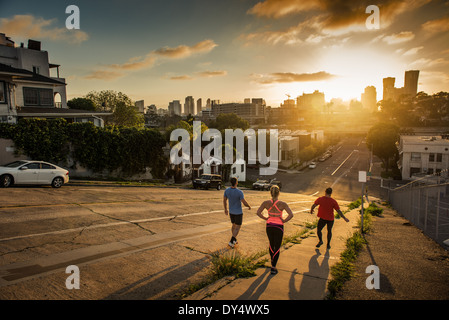 Il team di guide di scorrimento correre giù per una ripida collina della città Foto Stock