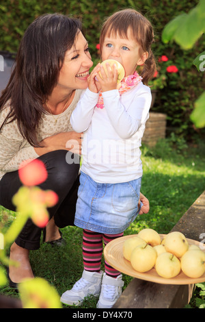 Madre e figlia raccogliendo mele in giardino Foto Stock