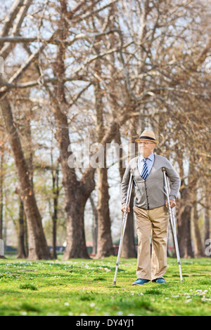 Anziano gentiluomo camminare con le stampelle in posizione di parcheggio Foto Stock