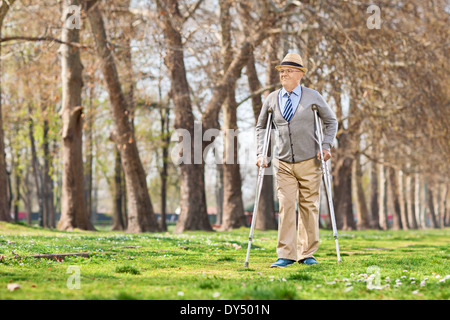 Senior gentleman camminando con le stampelle in posizione di parcheggio Foto Stock