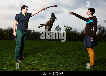Felice Coppia Giovane giocando con il loro cane salto nel Parco Foto Stock
