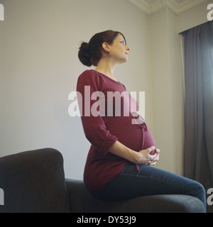 Donna incinta che guarda lontano Foto Stock