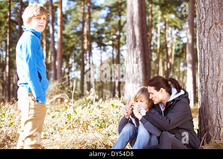 Donna matura esaminando i suoi figli ferito alla mano figlio nella foresta Foto Stock