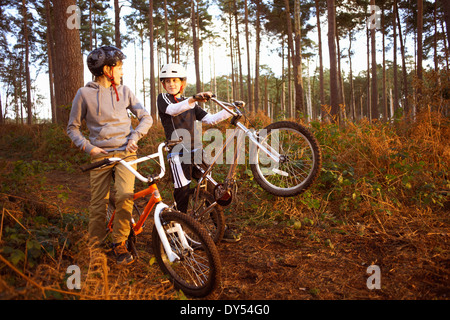 I fratelli gemelli azienda biciclette BMX chiacchierando in foresta Foto Stock