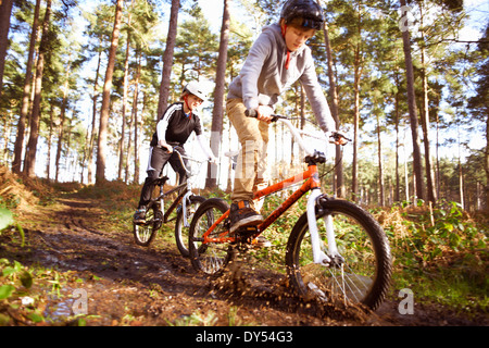 I fratelli gemelli racing BMX le biciclette attraverso la foresta fangose Foto Stock