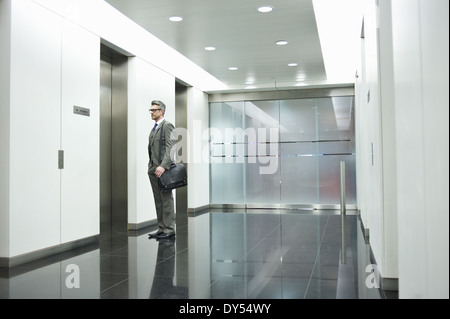 Imprenditore in attesa di ascensore nel corridoio di office Foto Stock