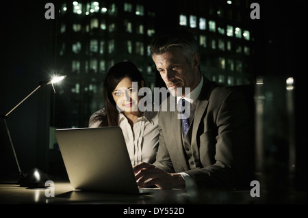 Colleghi di lavoro lavora fino a tardi in ufficio sul computer portatile Foto Stock