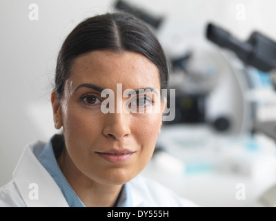 Ricercatore femmina in laboratorio accanto a microscopi. Foto Stock