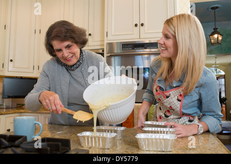 Donna Senior e nipote versando la miscela in teglie Foto Stock