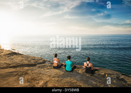 La donna seduta sulla scogliera, guardando il mare e la meditazione Foto Stock