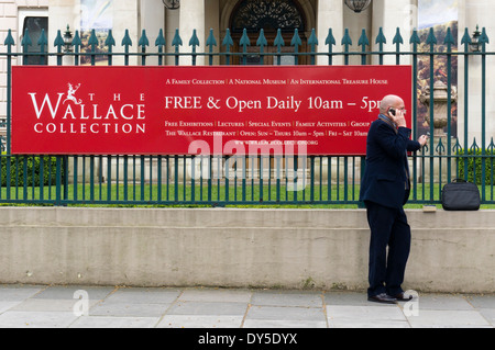 Uomo che utilizza il suo telefono mobile al di fuori della Wallace Collection di Londra. Foto Stock