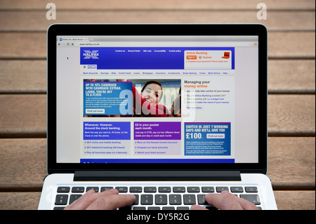 Il sito web di Halifax sul MacBook contro una panca in legno sfondo all'aperto tra cui un uomo le dita (solo uso editoriale). Foto Stock