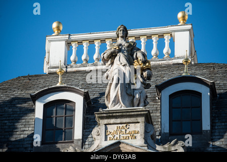 BRUXELLES, Belgio — Una statua decorativa adorna il tetto di uno degli edifici storici della Grand Place, la piazza centrale di Bruxelles. Il sito Patrimonio dell'Umanità dell'UNESCO presenta caratteristici stili architettonici gotici e barocchi risalenti alla fine del XVII secolo. Un'iscrizione sotto la statua recita "DOMVS WOOLEN Exalted". Foto Stock