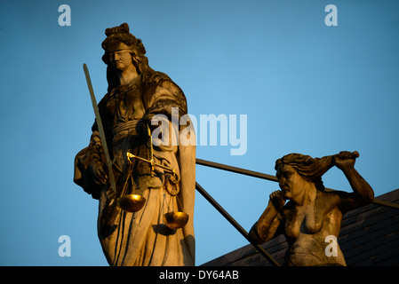 BRUGES, Belgio: La luce del sole del mattino presto illumina la statua della giustizia che incorona la casa barocca del Provosto (Proosdij) in Piazza Burg. Costruito nel 1666, questo edificio storico contrasta con il gotico Municipio di fronte. L'ex residenza del vescovo, ora sede di uffici governativi provinciali, dimostra l'evoluzione dell'architettura civica a Bruges. Foto Stock