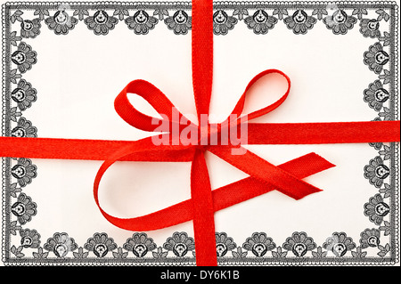 Carta regalo con un nastro rosso e pizzo floreale telaio Foto Stock
