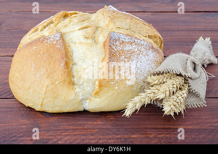 Tradizionale pane rotondo con un paio di spighe di grano su un tavolo di legno Foto Stock