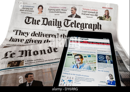 Tablet con online notizie internazionali sulla sommità del britannico Daily Telegraph e il francese Le Monde quotidiani su sfondo bianco Foto Stock