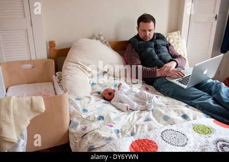 Padre con il suo neonato su un letto guardando preoccupato Foto Stock