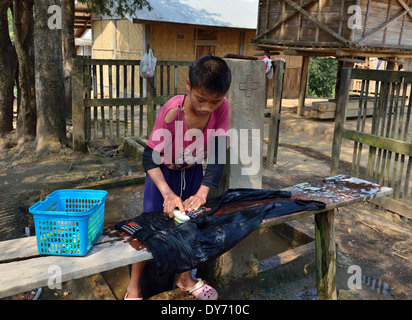 Uomo tribù Hmong lavando i pantaloni a mano nel suo villaggio accanto al fiume Mekong, Laos, Sud-est asiatico Foto Stock