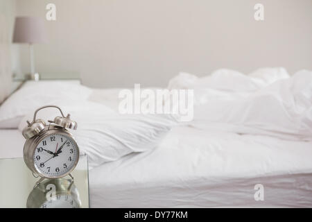 Sveglia sul comodino e vista offuscata della giovane donna che non vuole  svegliarsi, coprendo le orecchie con cuscino nel letto Foto stock - Alamy