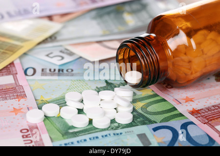 Immagine simbolica per il costo elevato della medicina con le pillole sul denaro Foto Stock