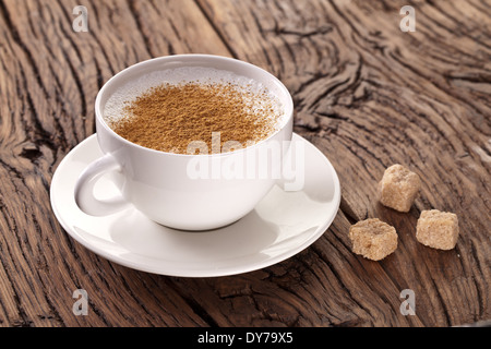 Tazza di cappuccino con cannella in polvere e zucchero i cubi su piastra. Foto Stock