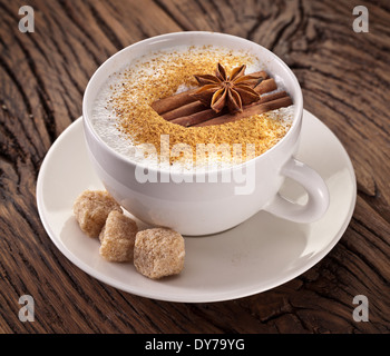 Tazza di cappuccino decorato con spezie e cubetti di zucchero di canna in prossimità di essa. Foto Stock