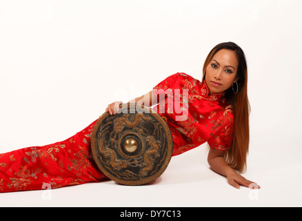 Gong cinese detenute da un asiatico o Oriental lady in un rosso vestito tradizionale Foto Stock