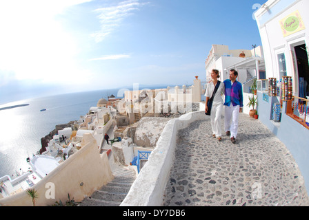 Un paio di passeggiare davanti un storefont e godendo la vista di Oia - Santorini, Grecia. Foto Stock