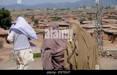 Islamabad, Pakistan. 8 Aprile, 2014. fghan donne rifugiate a piedi passato una casa di fango nella baraccopoli zona di Islamabad il 8 aprile 2014. Secondo le Nazioni Unite Agenzia per i Rifugiati, UNHCR, vi sono circa 2,6 milioni di afghani registrati in Pakistan, la maggior parte dei quali hanno vissuto qui fin dai primi anni ottanta quando l'ex Unione Sovietica hanno invaso la loro patria. Con poche opportunità per rendere la loro livings in Pakistan, vogliono tornare a casa loro ma solo dopo il ripristino della pace in Afghanistan. Credito: PACIFIC PRESS/Alamy Live News Foto Stock