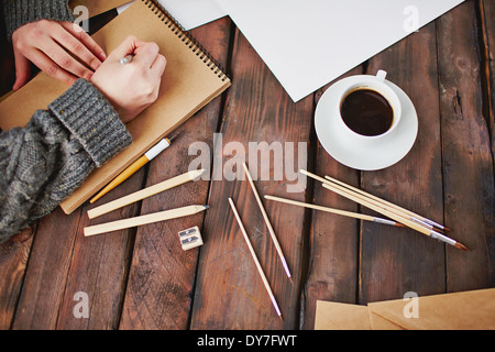 Immagine della tazza di caffè e oggetti per il disegno a mano e il maschio con le mani su blocco note Foto Stock