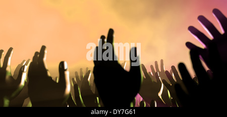 Una folla di visualizzazione a livello di mani sollevate dalla folla di spettatori intervallati da colorati faretti e un atmosfera piena di fumo Foto Stock