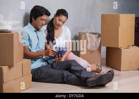 Felice coppia seduta sul pavimento con il tablet Foto Stock