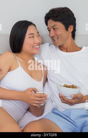 Felice coppia avente la colazione a letto Foto Stock