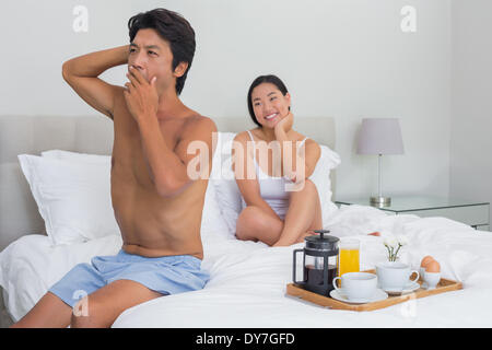 Donna sorridente a guardare il suo fidanzato sbadiglio e stretch Foto Stock