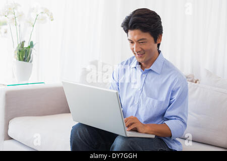 Felice l'uomo seduto sul lettino usando computer portatile Foto Stock