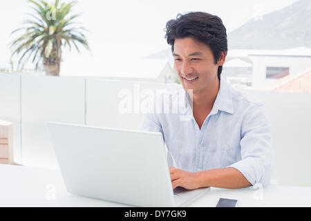 Uomo sorridente con il suo computer portatile Foto Stock