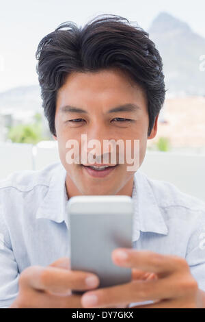 Uomo sorridente inviando un messaggio di testo Foto Stock