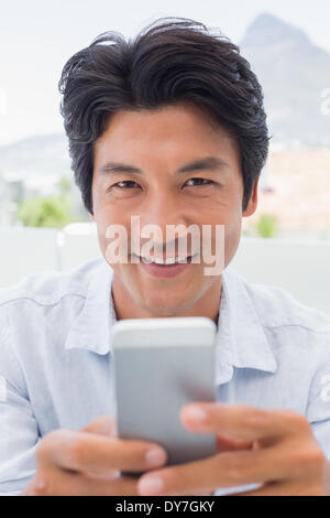 Uomo sorridente inviando un messaggio di testo Foto Stock