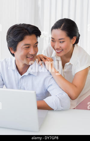 Felice coppia utilizzando laptop insieme Foto Stock