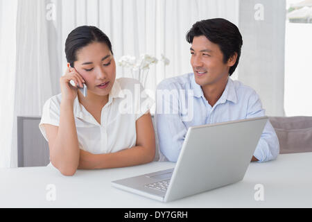 Paio utilizzando computer portatile con la donna che parla al telefono Foto Stock