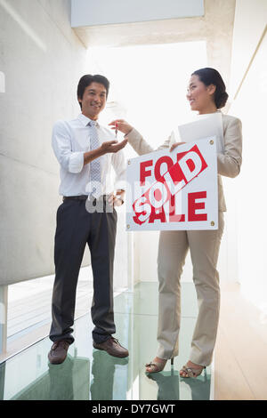 Agente immobiliare che dà le chiavi al nuovo proprietario di casa Foto Stock