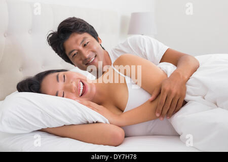 Sorridente coppia giacendo in letto Foto Stock