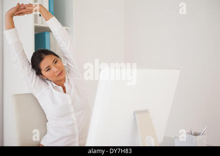 Casual imprenditrice stretching alla sua scrivania Foto Stock