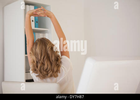 Casual imprenditrice stretching alla sua scrivania Foto Stock