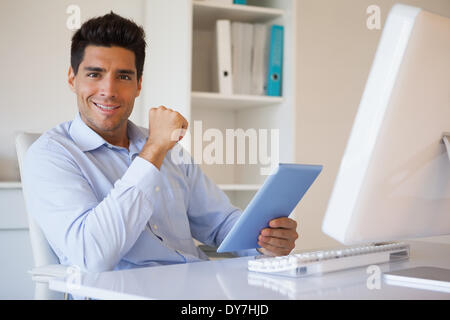 Imprenditore Casual tenendo la sua compressa alla sua scrivania Foto Stock