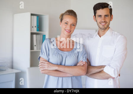 Casual business team sorridente in telecamera con le braccia incrociate Foto Stock