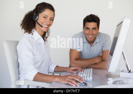 Casual business team sorridente in telecamera insieme alla scrivania Foto Stock