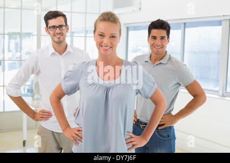 Casual business team sorridente in telecamera con le mani sui fianchi Foto Stock